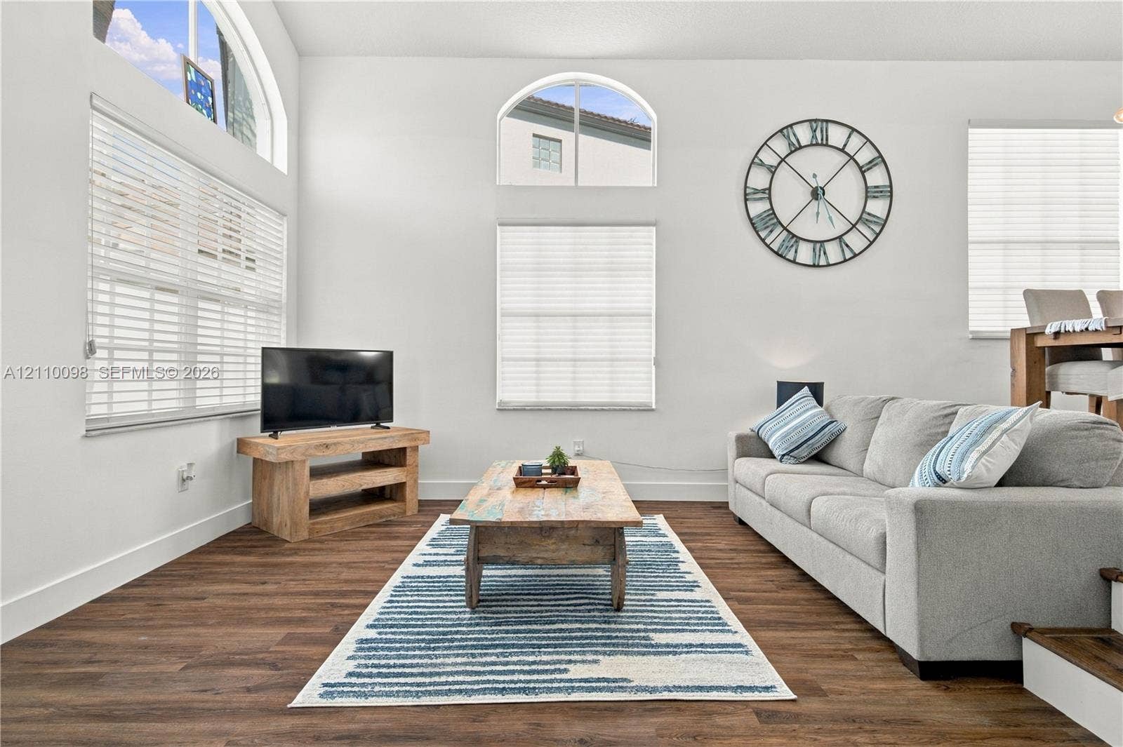 Living area featuring vaulted ceilings, wood-finish flooring, and arched windows providing natural light