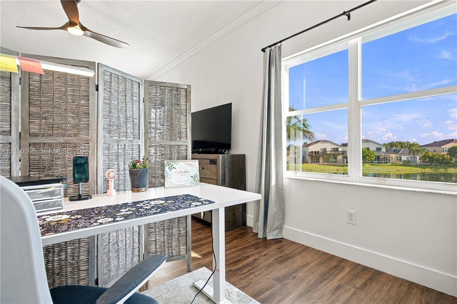 Multi-pane window with exterior water backdrop, wood-finish flooring, and ceiling fan with integrated lighting