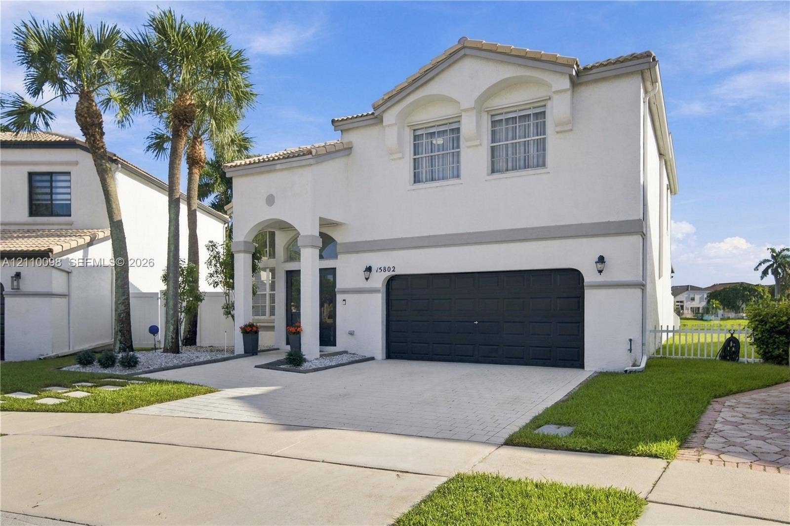 Two-story stucco exterior featuring an arched entryway, decorative trim, a multi-car garage, and a paved driveway