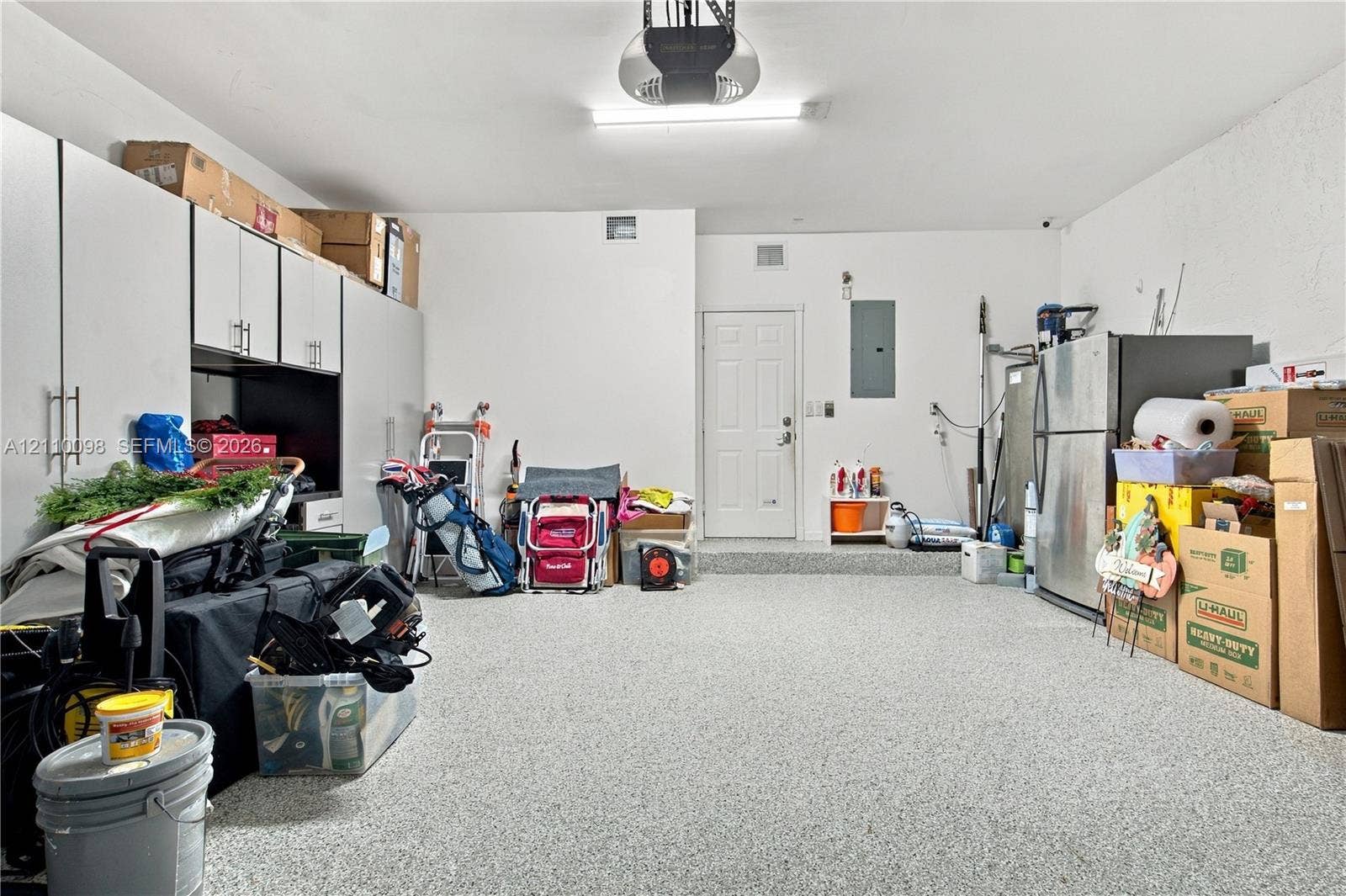 Garage featuring an epoxy floor finish, built-in white cabinetry with bar pulls, and a dedicated exterior-access door