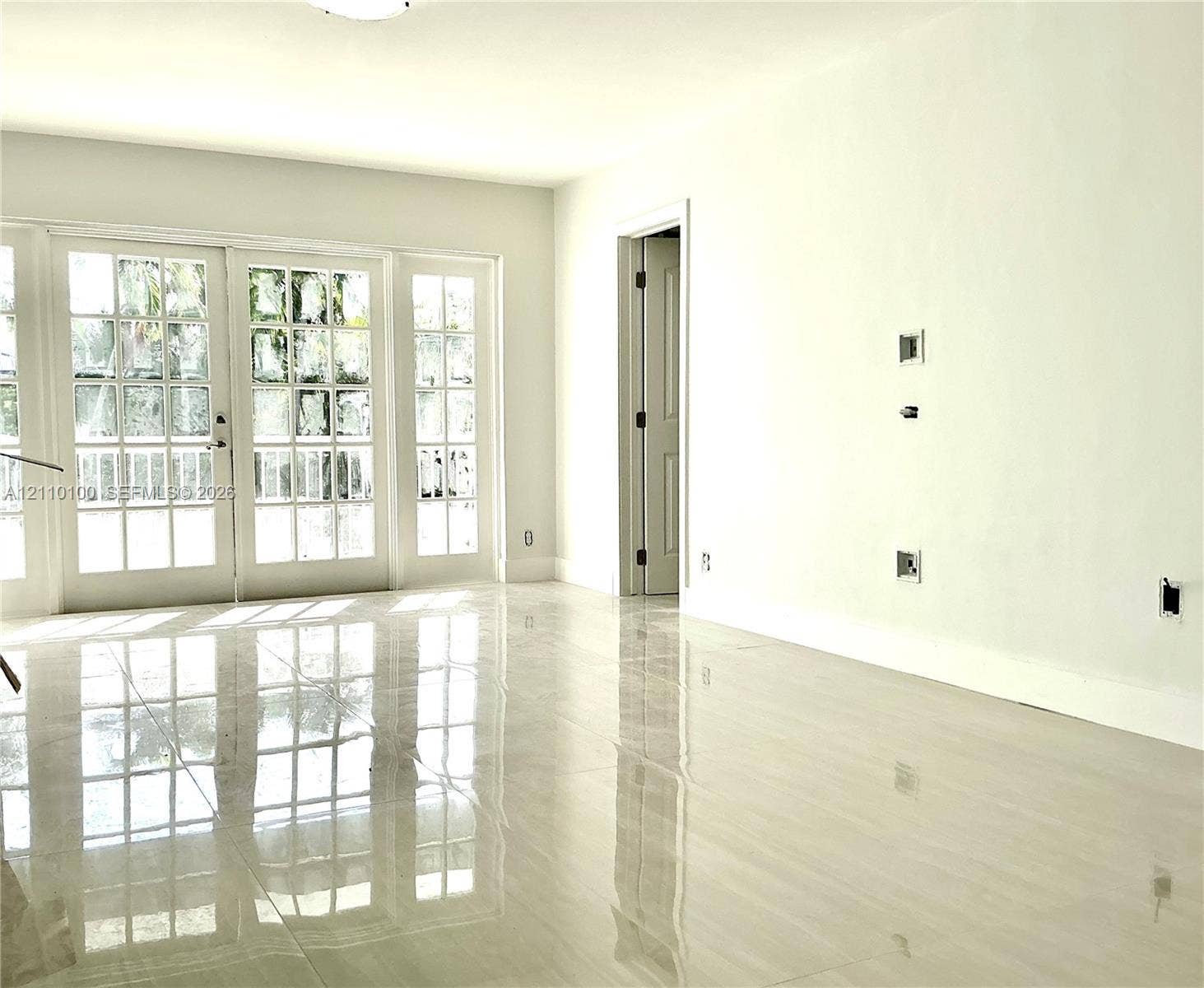 Polished neutral-tone tile flooring, multi-pane glass French doors, and smooth wall finish