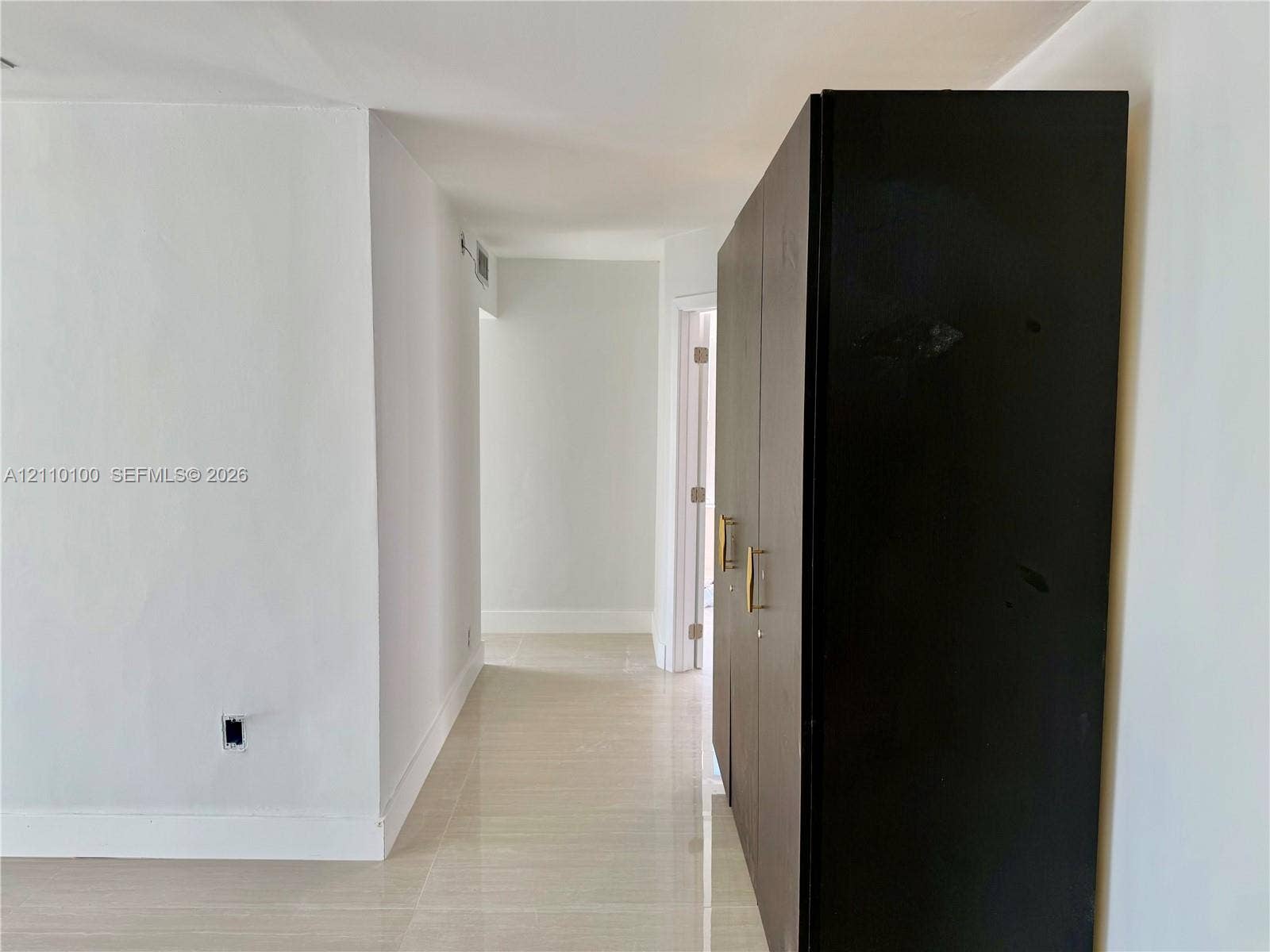 Neutral-toned tile flooring throughout with built-in, full-height dark cabinetry featuring metallic pulls and smooth walls