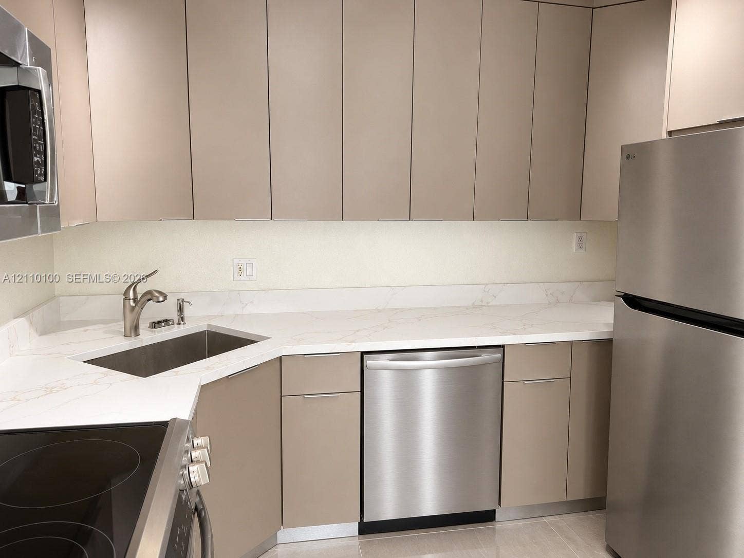 Kitchen featuring slab-style cabinetry, stone-finish countertops, stainless steel appliances, and a undermount sink with a gooseneck faucet