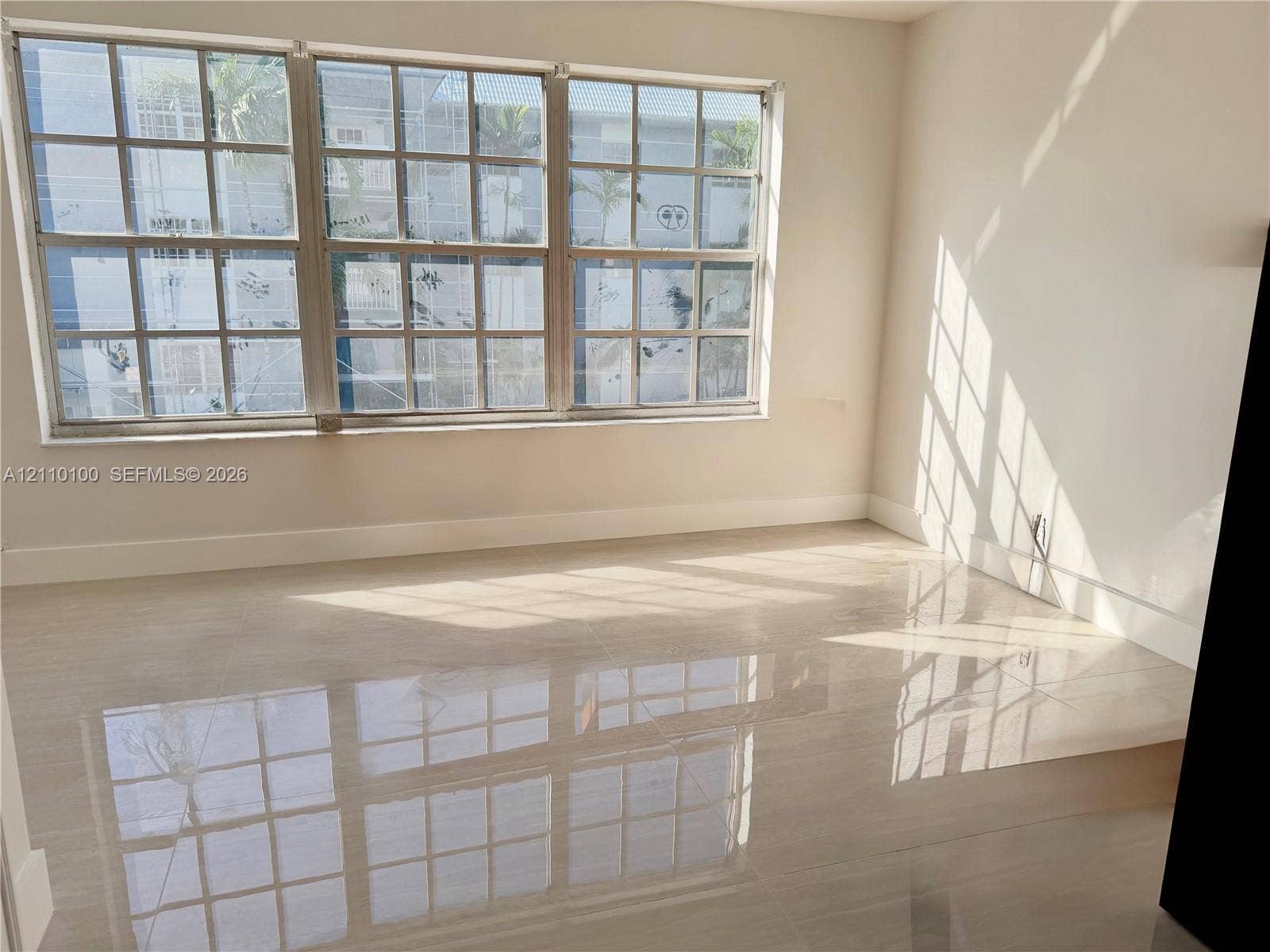 Large grid-pattern windows, neutral wall paint, and polished stone-finish tile flooring