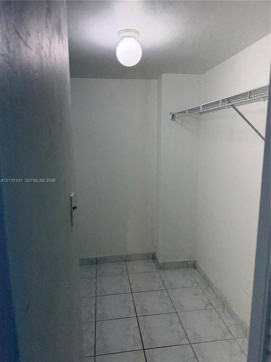 10850 N Kendall Drive, #412, Miami, Miami, FL 33176 Storage space featuring ceramic tile flooring, a wall-mounted wire shelving unit, and a flush-mount globe light fixture