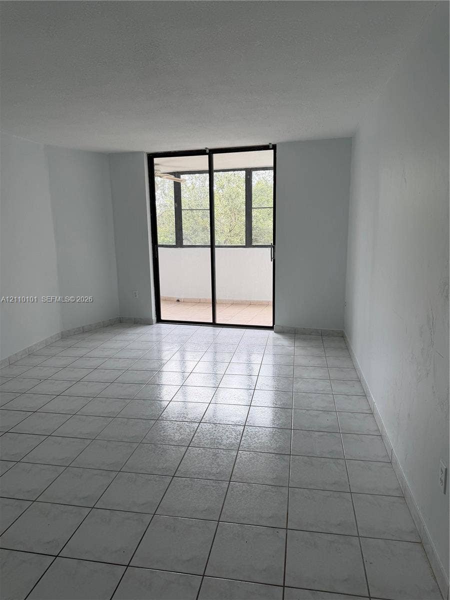 10850 N Kendall Drive, #412, Miami, Miami, FL 33176 Interior space featuring large-format tile flooring and floor-to-ceiling sliding glass doors leading to a covered balcony