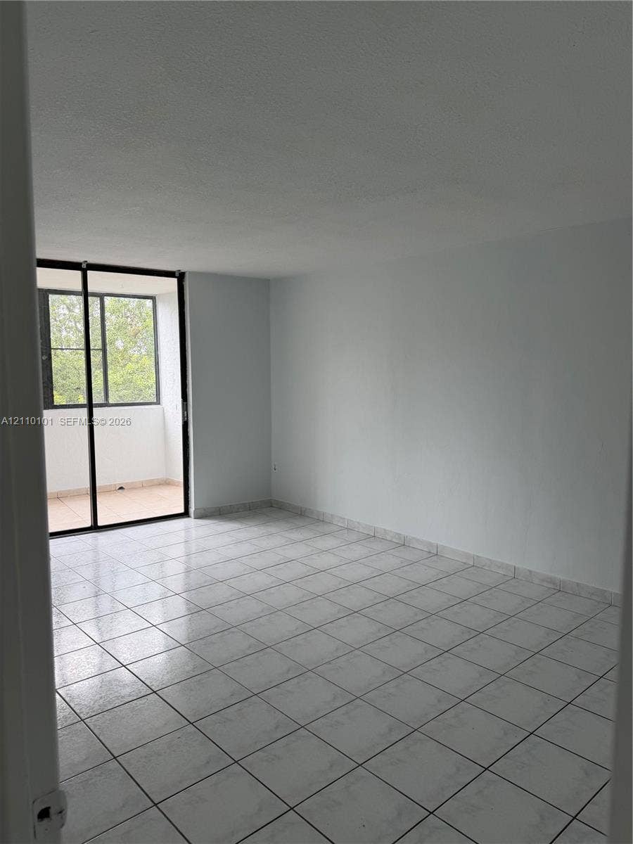 10850 N Kendall Drive, #412, Miami, Miami, FL 33176 Interior space featuring ceramic tile flooring, neutral walls, and large glass sliding doors providing exterior access
