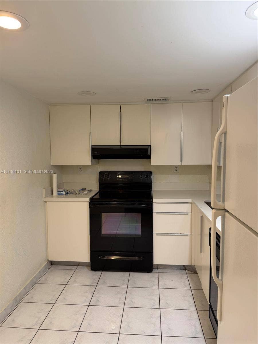 10850 N Kendall Drive, #412, Miami, Miami, FL 33176 Kitchen featuring matte finish cabinetry, black range, integrated range hood, solid surface countertops, and tile flooring