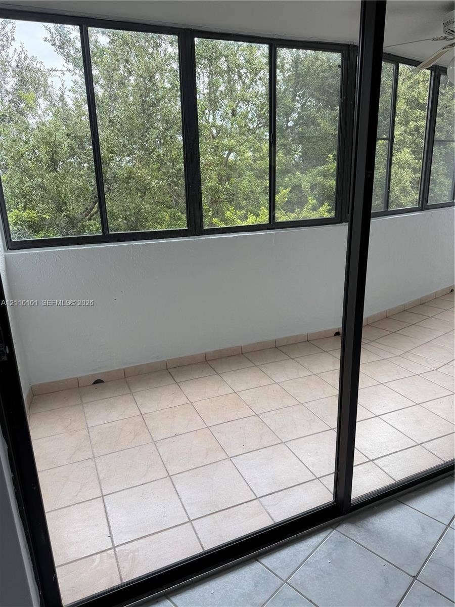 10850 N Kendall Drive, #412, Miami, Miami, FL 33176 Enclosed porch featuring tile flooring, expansive window panels, and a ceiling fan