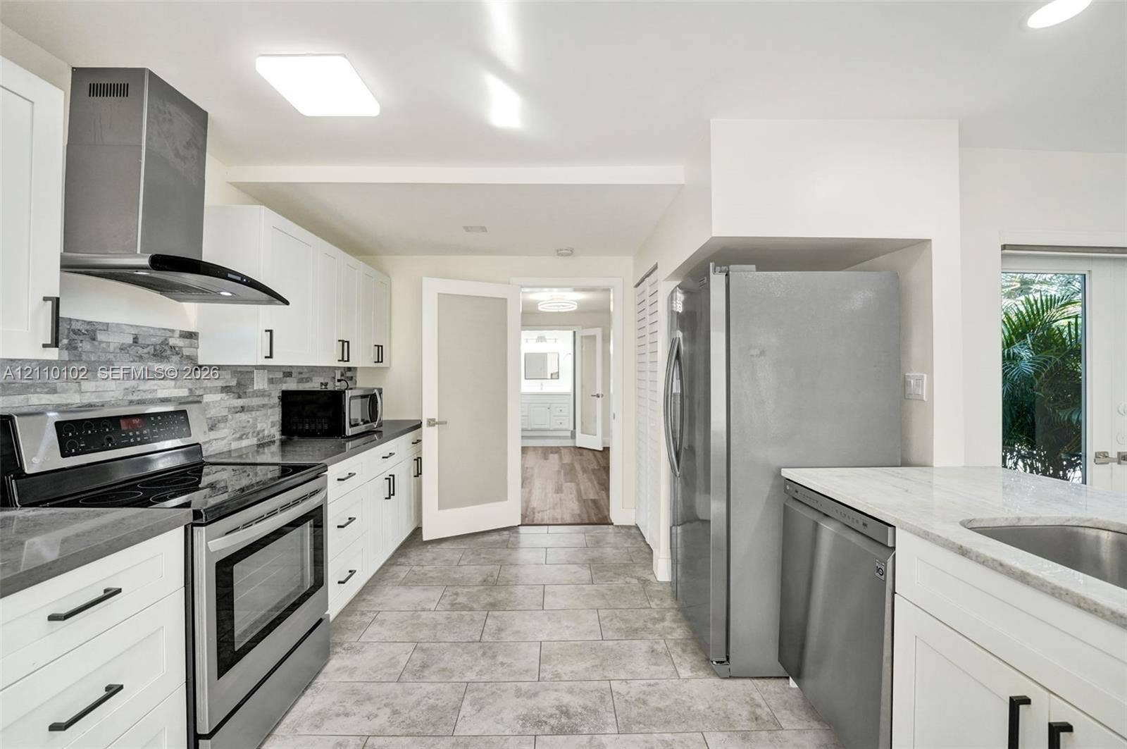 1224 NE 13th Avenue, #2, Fort Lauderdale, Fort Lauderdale, FL 33304 Kitchen featuring white shaker cabinetry, stone-tile backsplash, stainless steel appliances, stone-look countertops, and neutral tile flooring