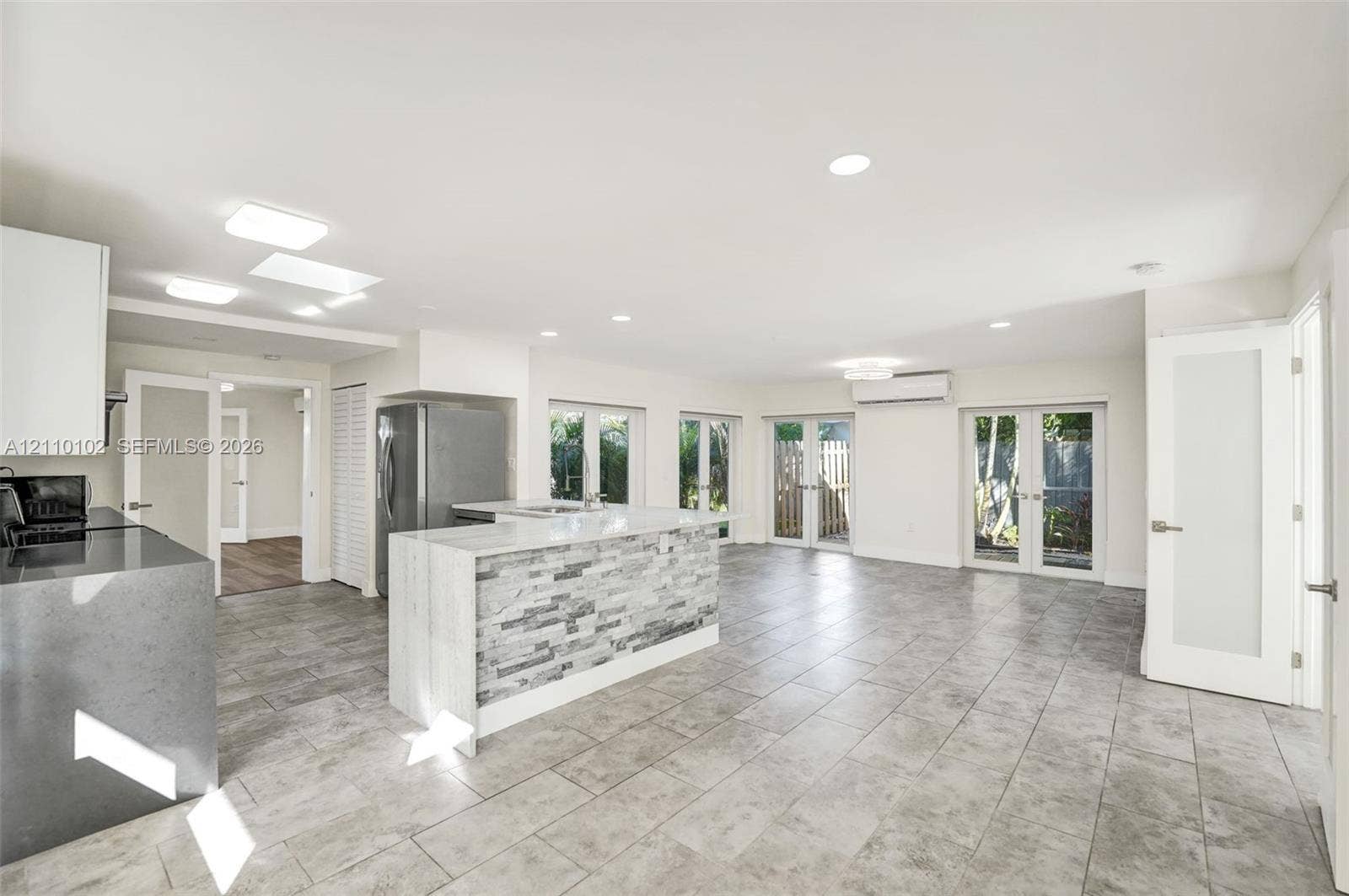 1224 NE 13th Avenue, #2, Fort Lauderdale, Fort Lauderdale, FL 33304 Open-concept kitchen featuring an island with stone-tile cladding and quartz countertops, gray ceramic tile flooring, recessed lighting, and multiple sets of French doors