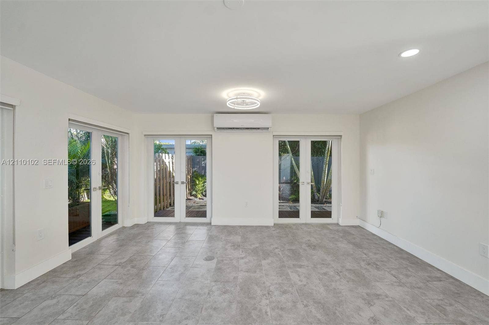 1224 NE 13th Avenue, #2, Fort Lauderdale, Fort Lauderdale, FL 33304 Neutral-toned tile flooring, dual sets of glass-paned French doors, wall-mounted ductless climate control unit, and recessed ceiling lighting
