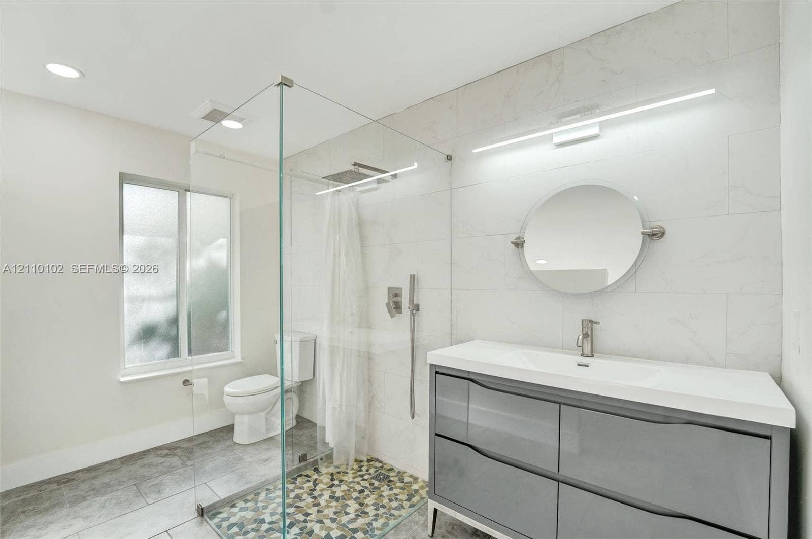 1224 NE 13th Avenue, #2, Fort Lauderdale, Fort Lauderdale, FL 33304 Floating vanity with dual soft-close drawers and integrated countertop, glass-enclosed shower with rainfall showerhead, pebble-tiled shower floor, and large-format wall tiling