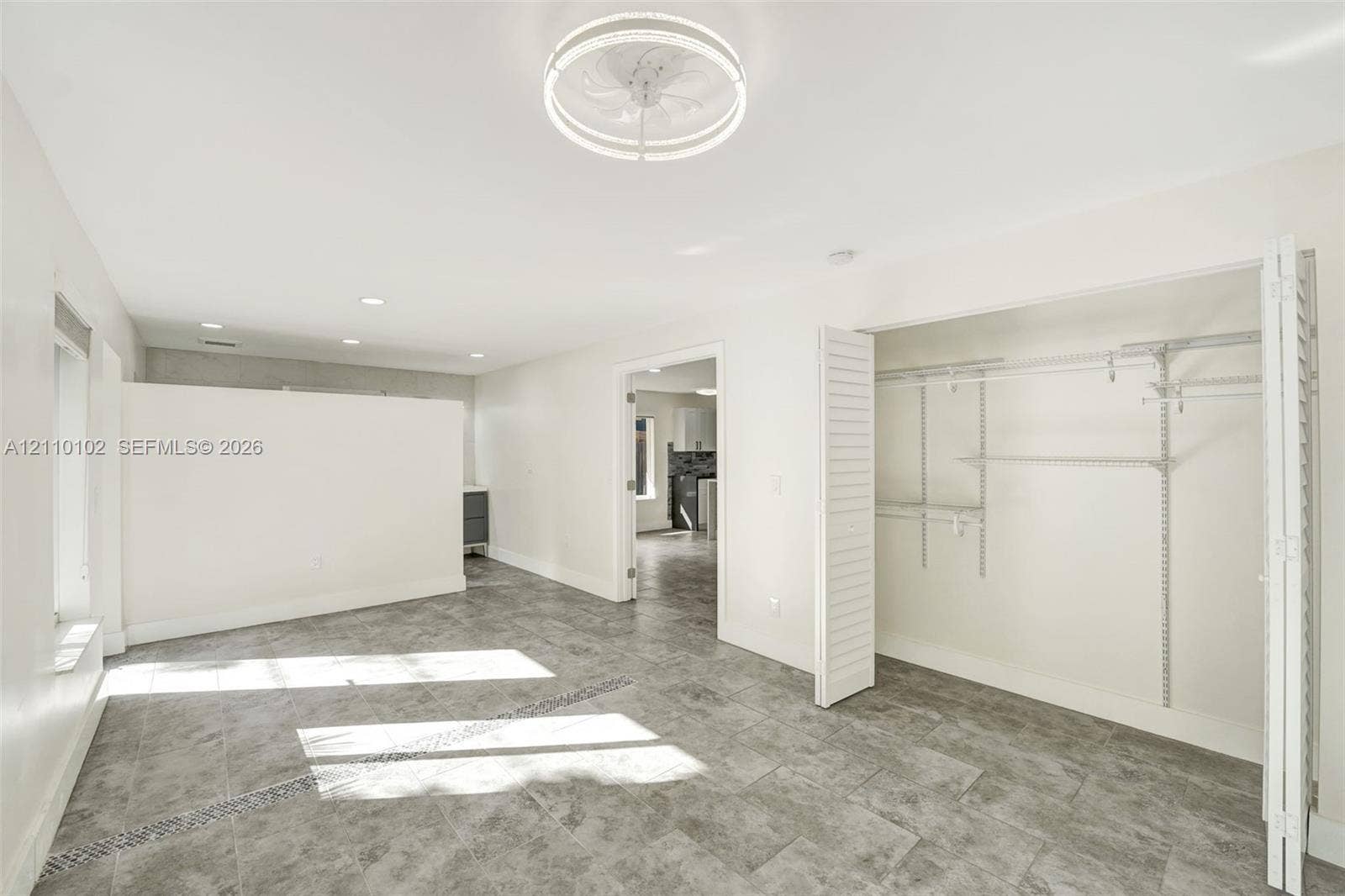 1224 NE 13th Avenue, #2, Fort Lauderdale, Fort Lauderdale, FL 33304 Room featuring large-format tile flooring, a contemporary circular flush-mount ceiling fixture, a partial privacy wall, and a closet with ventilated wire shelving behind louvered doors