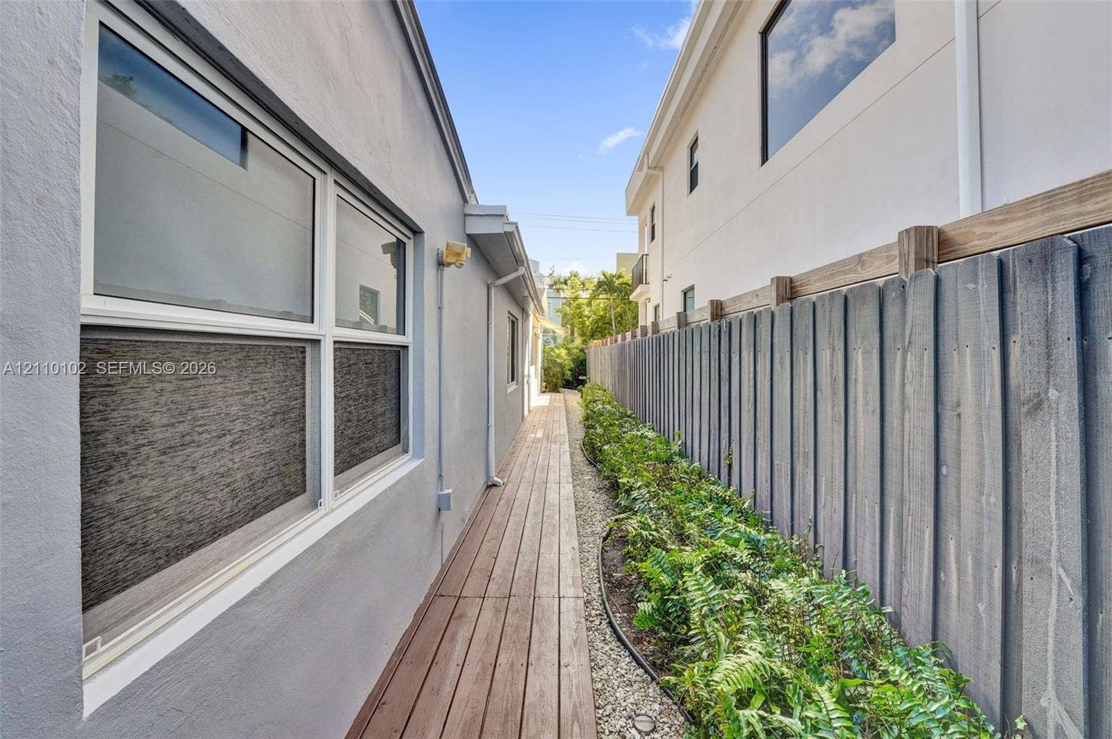 1224 NE 13th Avenue, #2, Fort Lauderdale, Fort Lauderdale, FL 33304 Exterior side walkway featuring wood-plank decking, a vertical wood privacy fence, and integrated landscaping with stone ground cover