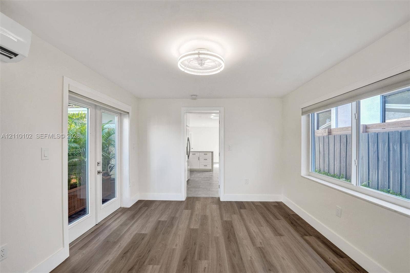 1224 NE 13th Avenue, #2, Fort Lauderdale, Fort Lauderdale, FL 33304 Room featuring wood-finish flooring, a wall-mounted ductless climate control unit, large sliding glass doors, a contemporary circular flush-mount ceiling light fixture, and horizontal windows