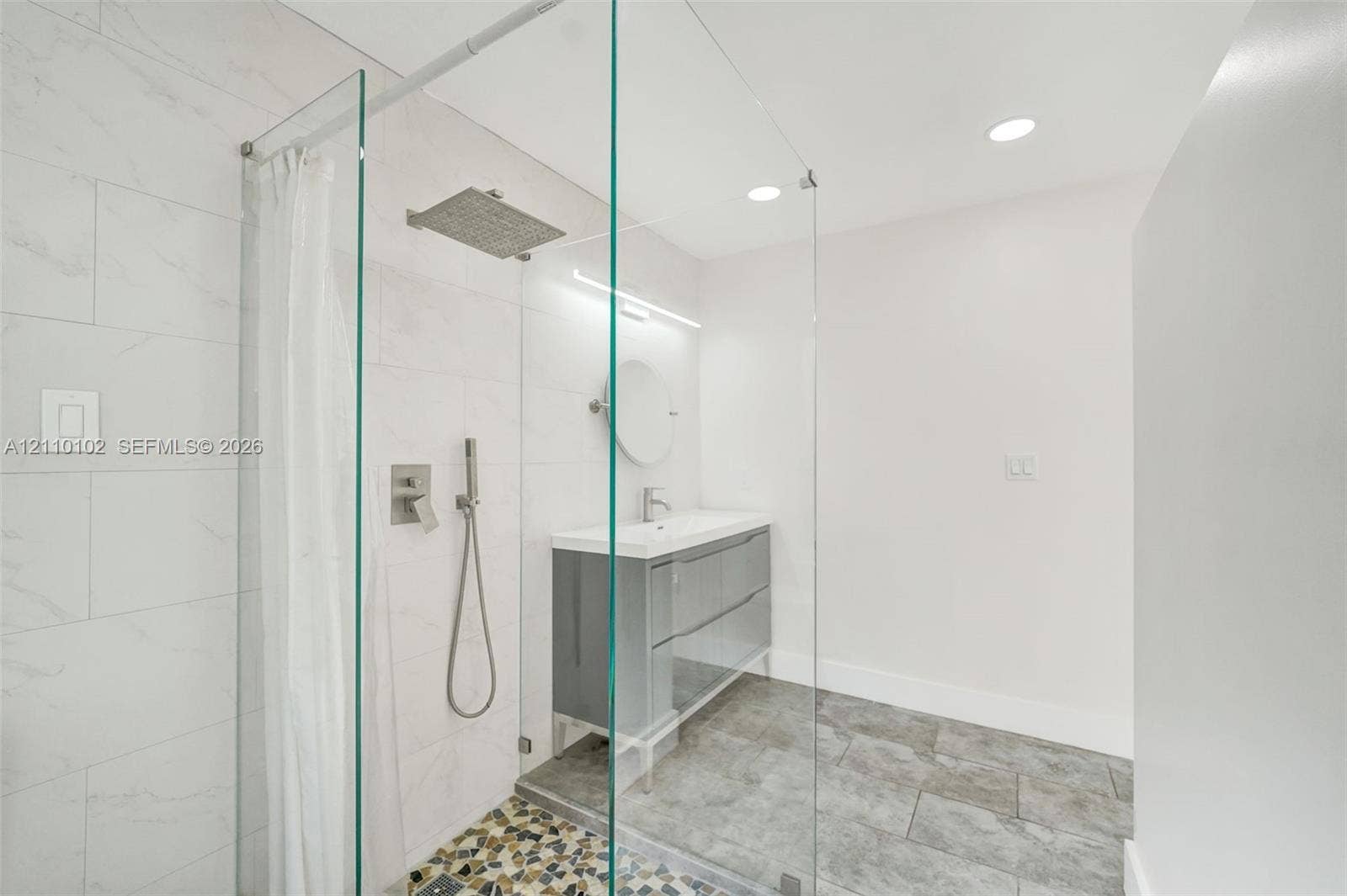 1224 NE 13th Avenue, #2, Fort Lauderdale, Fort Lauderdale, FL 33304 Walk-in shower featuring a glass enclosure, rainfall showerhead, and wall-mounted hand sprayer, complemented by a dual-drawer vanity with a white countertop and recessed lighting
