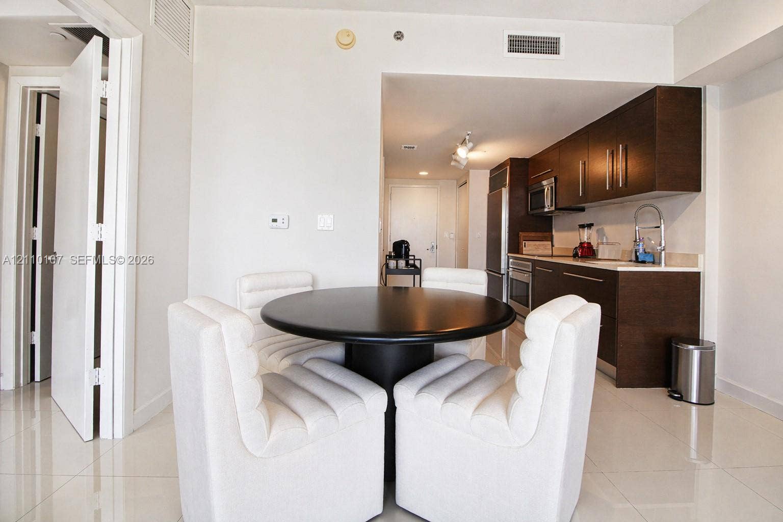 465 Brickell Avenue, #4604, Miami, Miami, FL 33131 Kitchen featuring dark wood-finish cabinetry, stainless steel appliances, and a gooseneck faucet, finished with polished tile flooring throughout