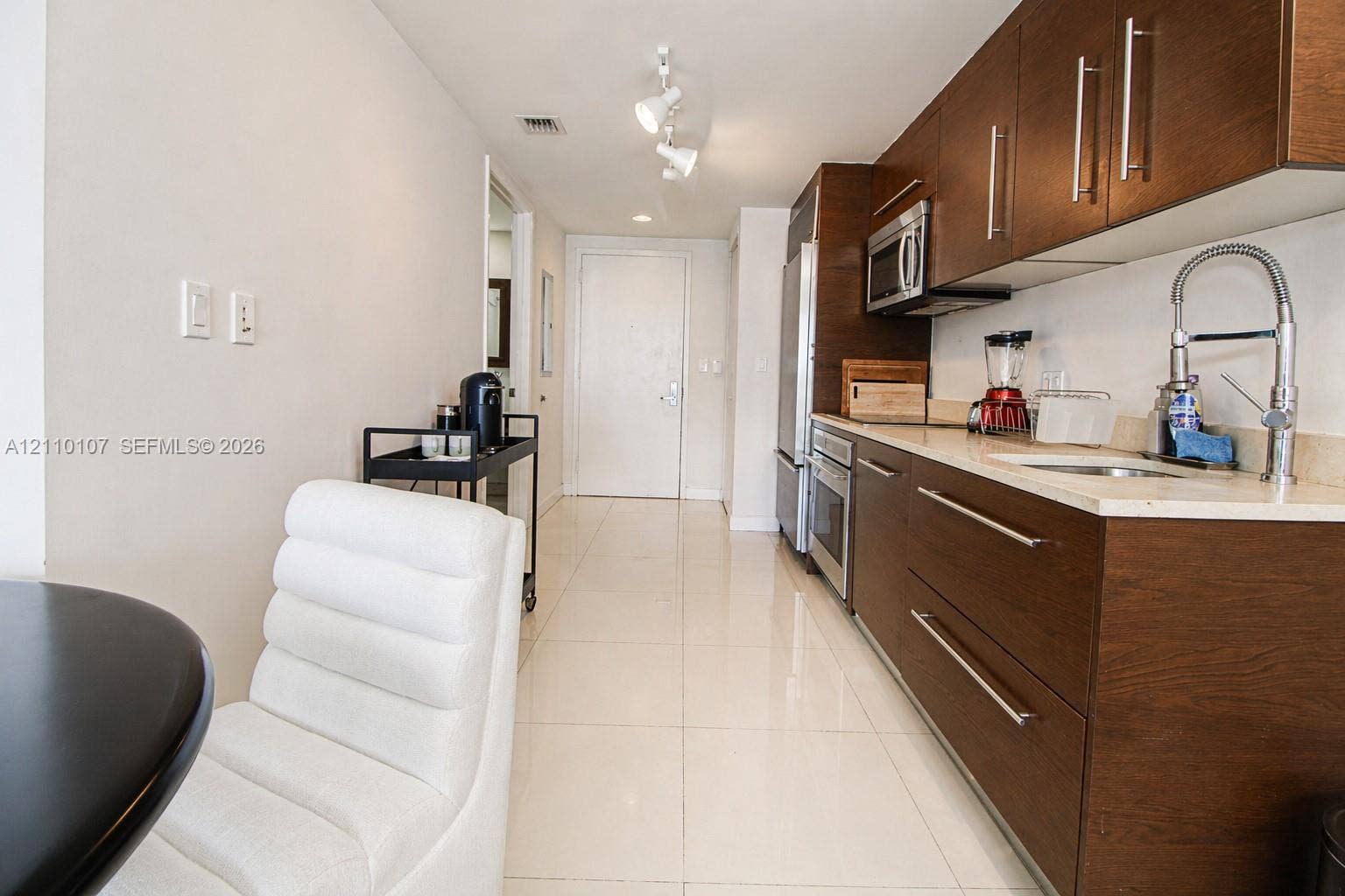 465 Brickell Avenue, #4604, Miami, Miami, FL 33131 Kitchen featuring flat-panel wood-finish cabinetry, light-toned stone countertops, stainless steel appliances, polished tile flooring, and a gooseneck faucet