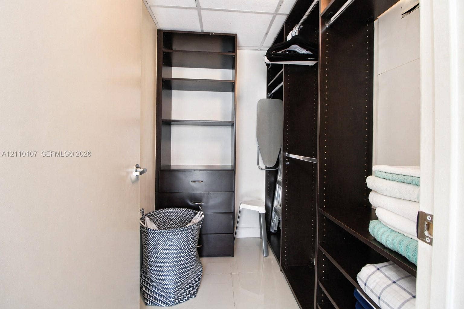 465 Brickell Avenue, #4604, Miami, Miami, FL 33131 Walk-in closet featuring dark wood-finish built-in shelving, integrated dresser drawers, and dual hanging rods