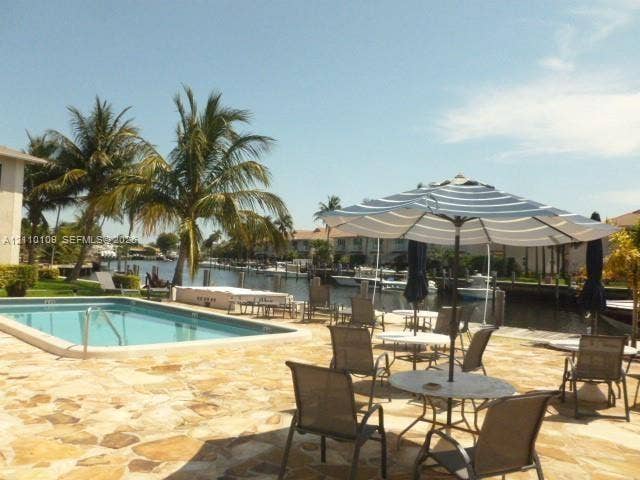 Waterfront patio featuring natural stone hardscaping, an in-ground swimming pool, and direct canal access