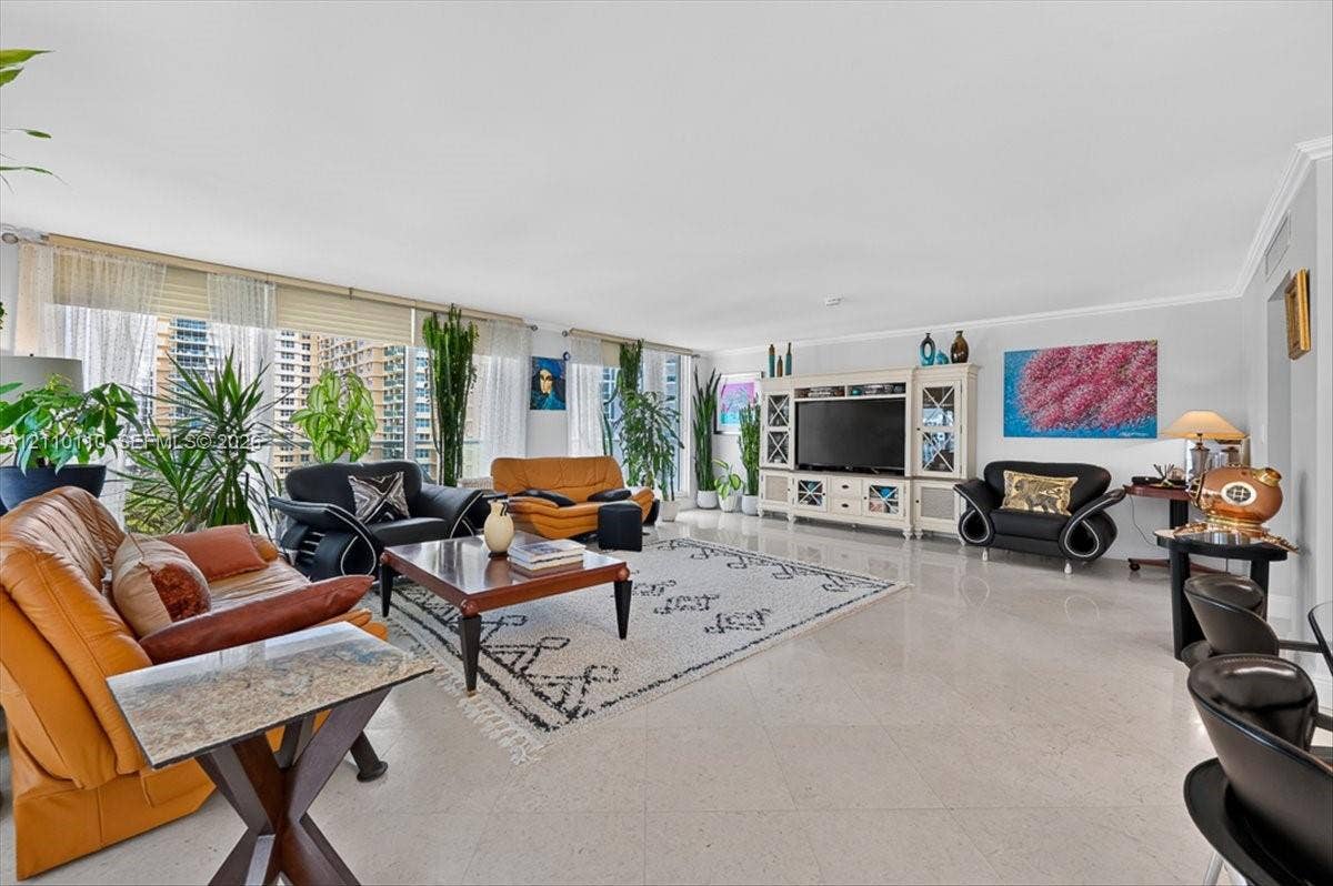 2751 S Ocean Drive, #801N, Hollywood, FL 33019 Expansive living area featuring large-format tile flooring, a floor-to-ceiling window wall with integrated blinds, and built-in cabinetry