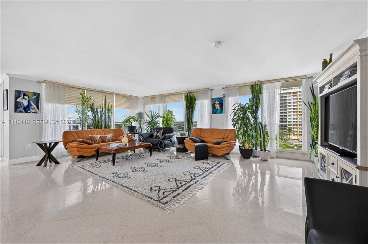 2751 S Ocean Drive, #801N, Hollywood, FL 33019 Expansive living area featuring large-format tile flooring, floor-to-ceiling windows, and custom built-in entertainment cabinetry