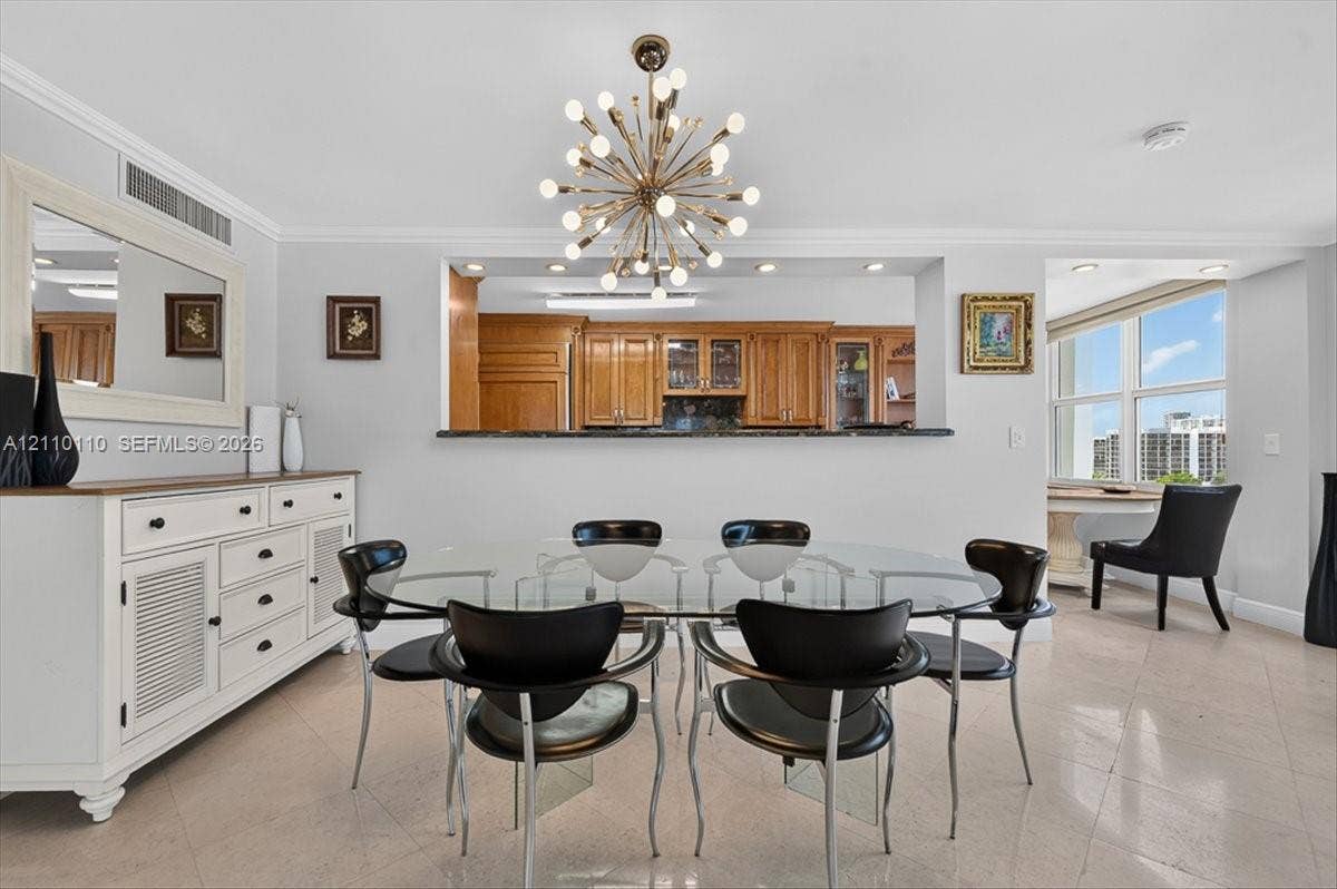 2751 S Ocean Drive, #801N, Hollywood, FL 33019 Dining area featuring a modern sputnik-style chandelier, tile flooring, crown molding, a built-in kitchen pass-through window with a stone countertop, and large windows