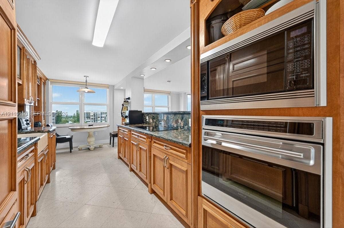 2751 S Ocean Drive, #801N, Hollywood, FL 33019 Kitchen featuring wood cabinetry, natural stone countertops, a farm-style apron sink, and built-in stainless steel double wall ovens and microwave