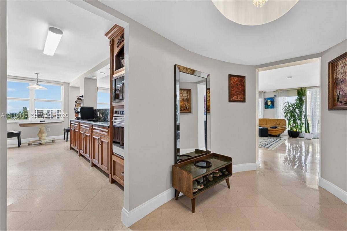 2751 S Ocean Drive, #801N, Hollywood, FL 33019 Curved interior wall, polished stone-finish flooring, custom wood cabinetry with integrated built-in oven, and recessed ceiling lighting