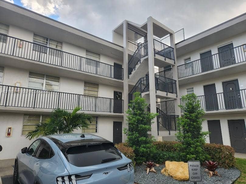 14185 SW 87th Street, #A110, Miami, FL 33183 Multi-story building exterior featuring a central concrete staircase, metal railings, and integrated landscaping with ornamental shrubs and stone accents