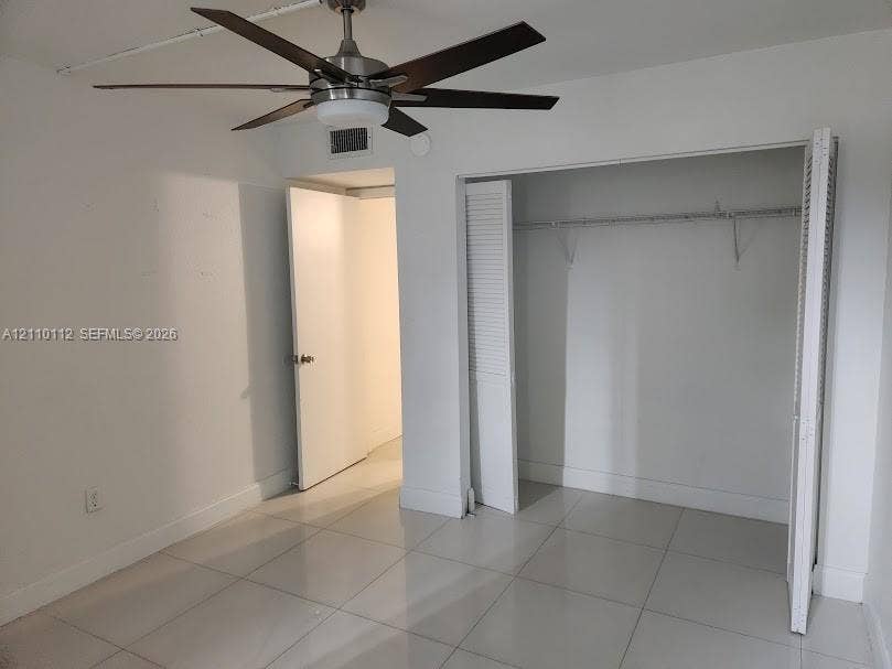 14185 SW 87th Street, #A110, Miami, FL 33183 Large-format neutral tile flooring, multi-blade ceiling fan with integrated lighting, and closet with louvered bi-fold doors