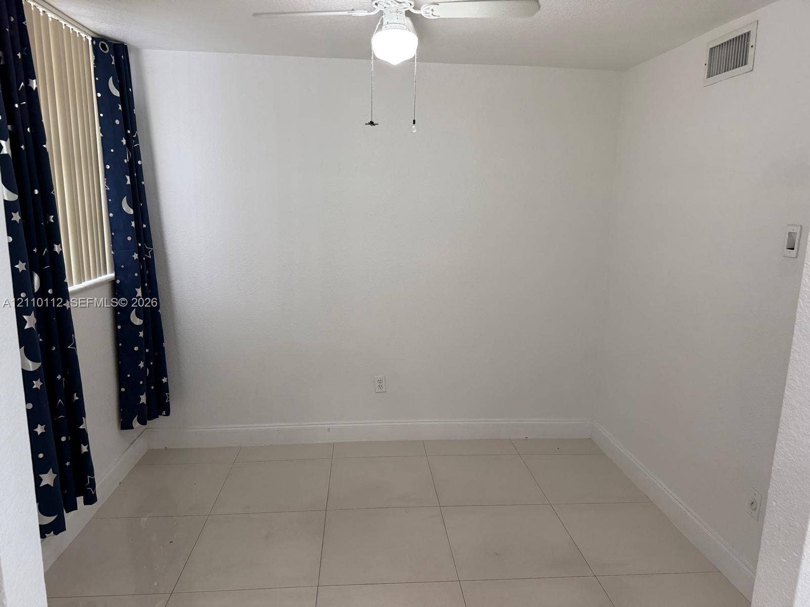14185 SW 87th Street, #A110, Miami, FL 33183 Room featuring large-format tile flooring, vertical blinds, and a central ceiling fan with an integrated light fixture