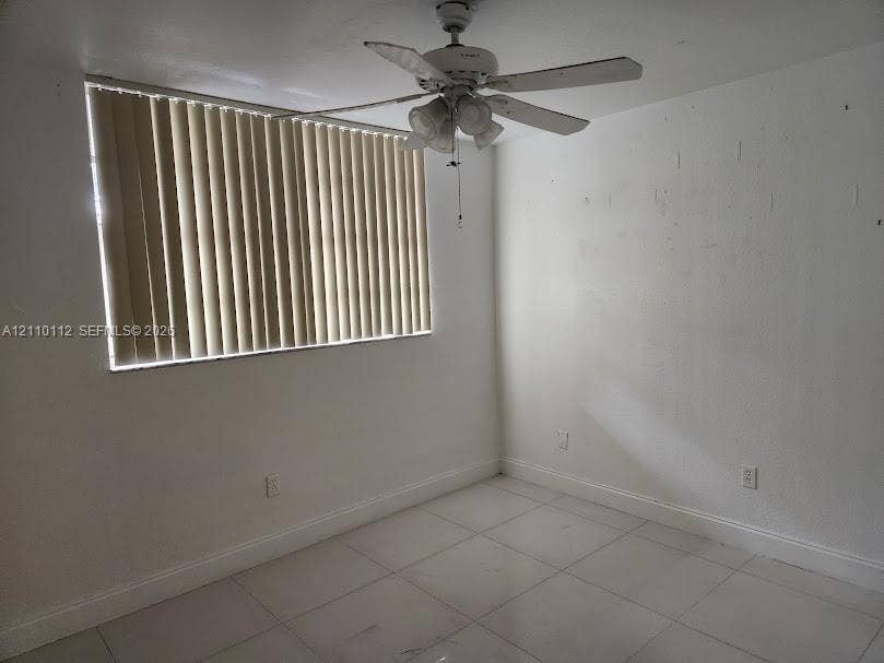14185 SW 87th Street, #A110, Miami, FL 33183 Room featuring white tile flooring, ceiling fan with integrated light fixture, and vertical window blinds