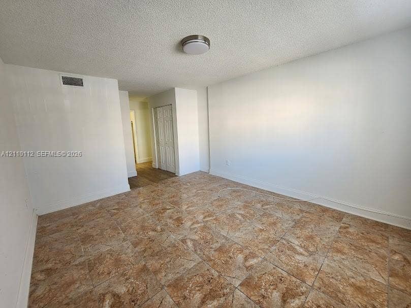 14185 SW 87th Street, #A110, Miami, FL 33183 Interior room featuring tile flooring, smooth white walls, and a recessed ceiling-mounted light fixture, complemented by double-door closet cabinetry