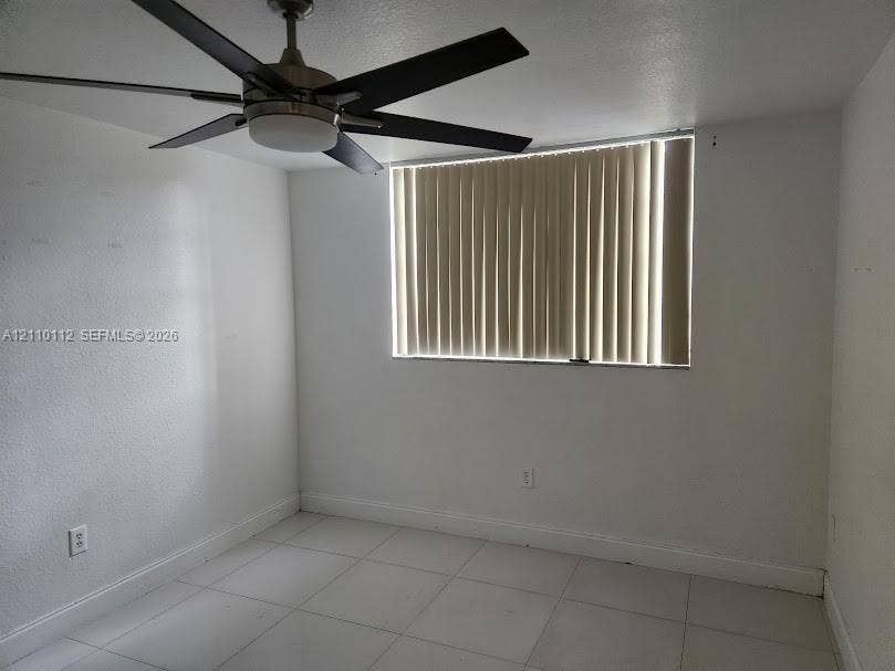 14185 SW 87th Street, #A110, Miami, FL 33183 Room featuring large-format ceramic tile flooring, a multi-blade ceiling fan with integrated lighting, and vertical window blinds