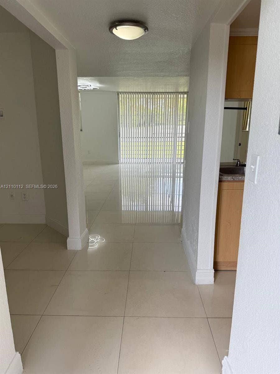 14185 SW 87th Street, #A110, Miami, FL 33183 Large-format tile flooring, flush-mount ceiling lighting, and vertical sliding glass door panels