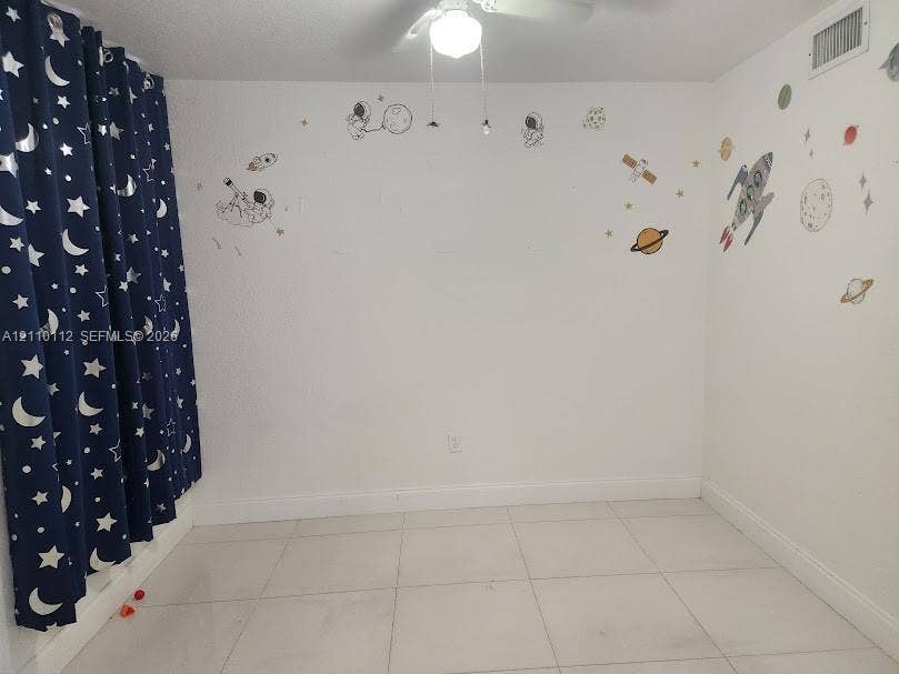 14185 SW 87th Street, #A110, Miami, FL 33183 Interior room featuring large-format ceramic tile flooring, neutral white walls, and a ceiling-mounted light fixture