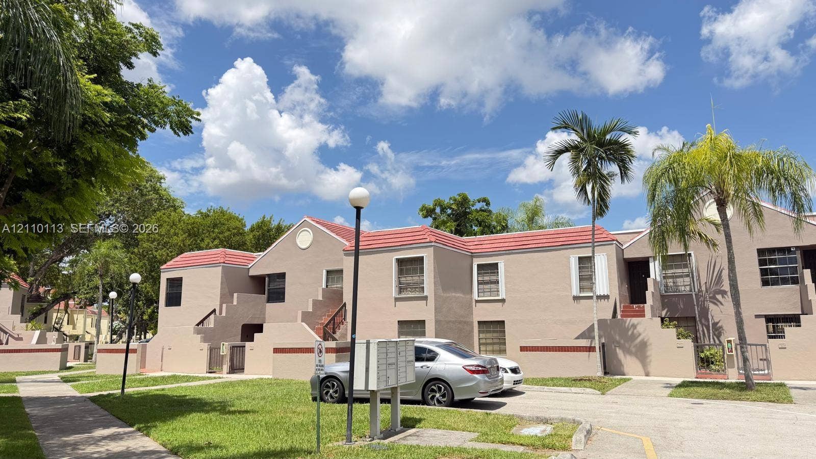 Multi-unit exterior featuring stucco siding, gabled roofs with tile surfacing, integrated staircases, and pedestrian walkways