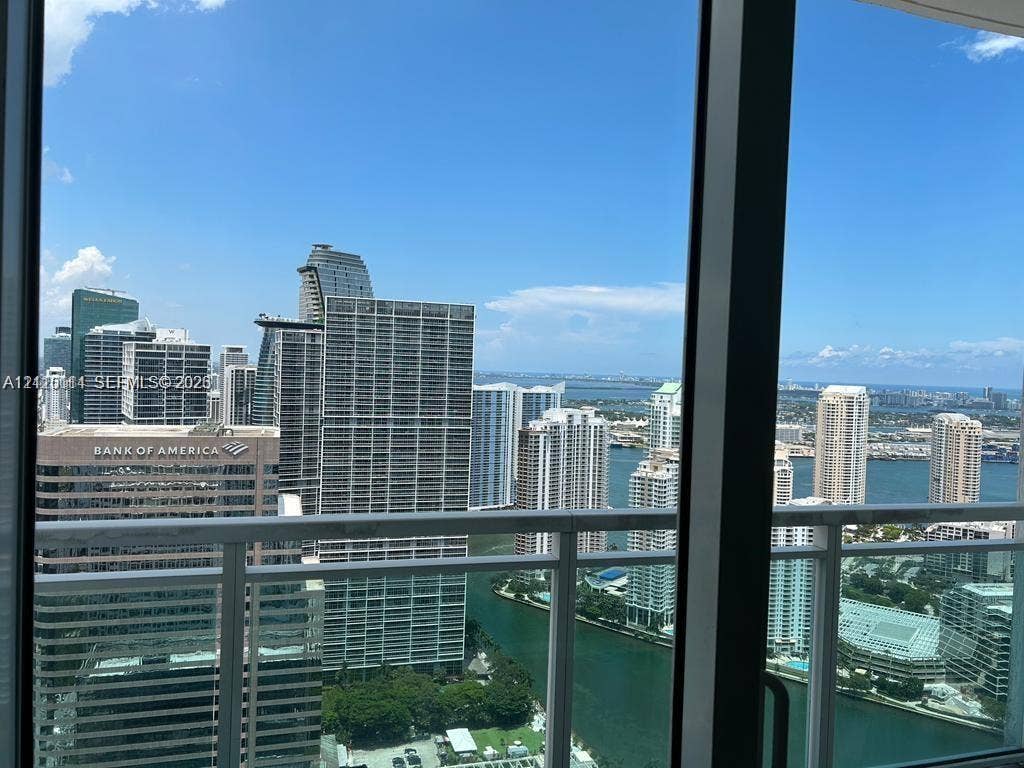 950 Brickell Bay Drive, #5108, Miami, Miami, FL 33131 Floor-to-ceiling glass windows and a glass-paneled balcony railing showcasing a cityscape and waterfront horizon