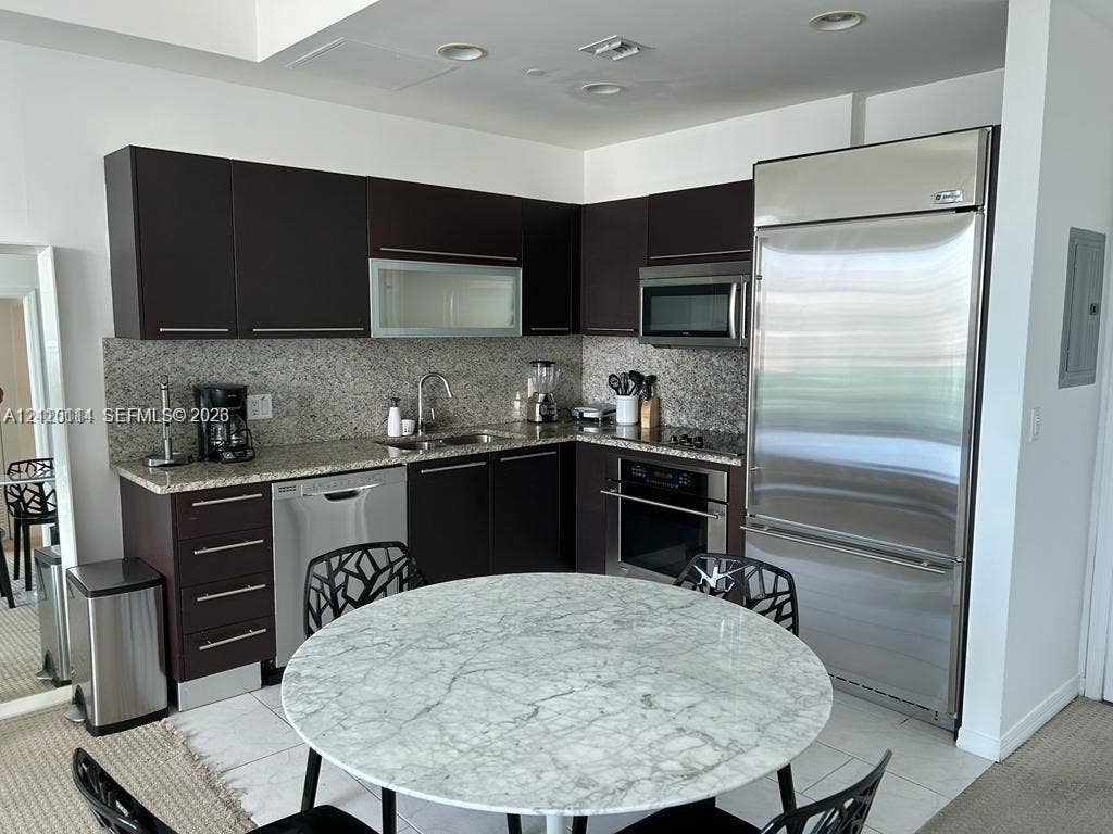 950 Brickell Bay Drive, #5108, Miami, Miami, FL 33131 Kitchen featuring dark-toned cabinetry, light stone countertops, integrated stainless steel refrigerator, built-in oven, and recessed lighting