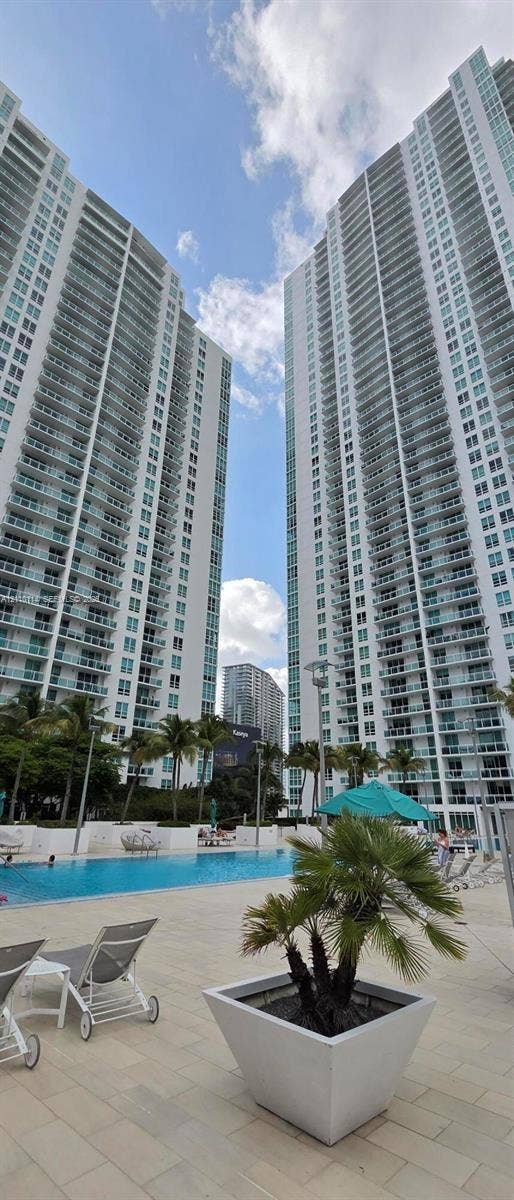 950 Brickell Bay Drive, #5108, Miami, Miami, FL 33131 High-rise towers featuring floor-to-ceiling glass paneling and private balconies, complemented by an outdoor swimming pool, paved sundeck, and palm tree landscaping