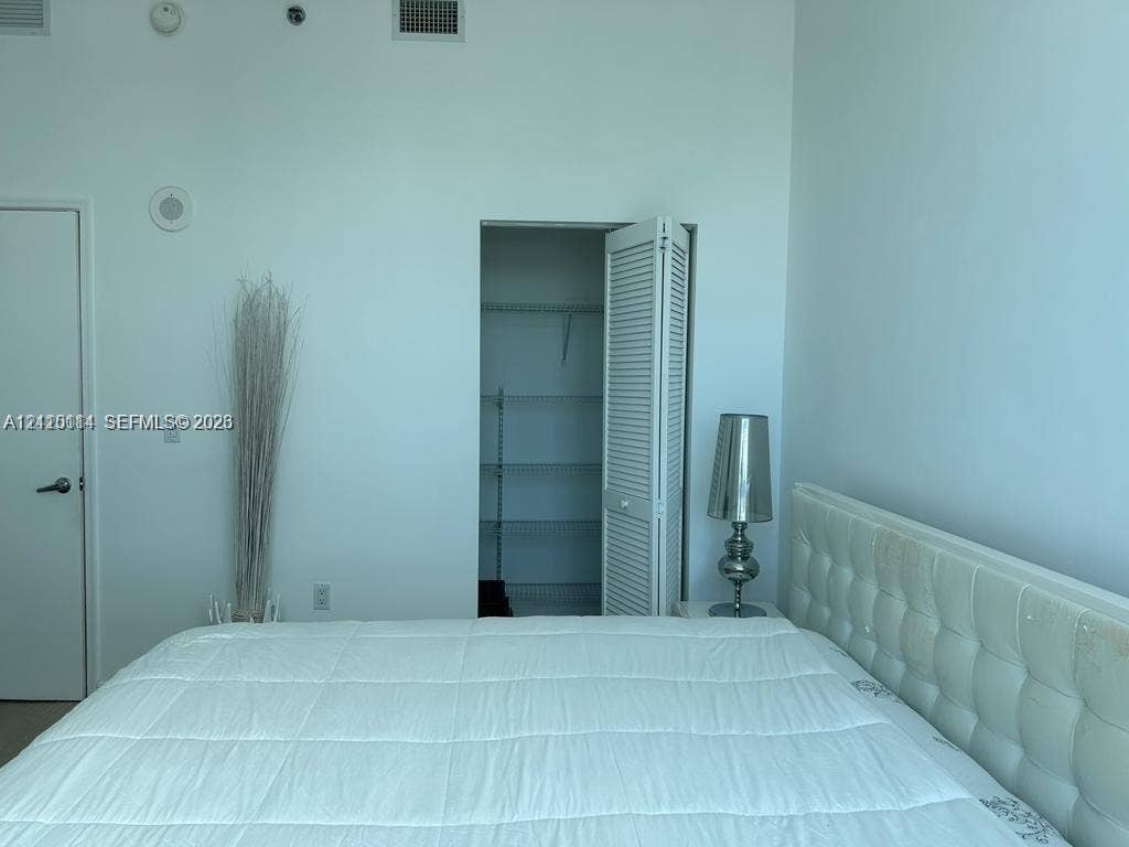 950 Brickell Bay Drive, #5108, Miami, Miami, FL 33131 High ceilings featuring integrated ceiling-mounted speakers and a walk-in closet with built-in shelving and louvered folding doors
