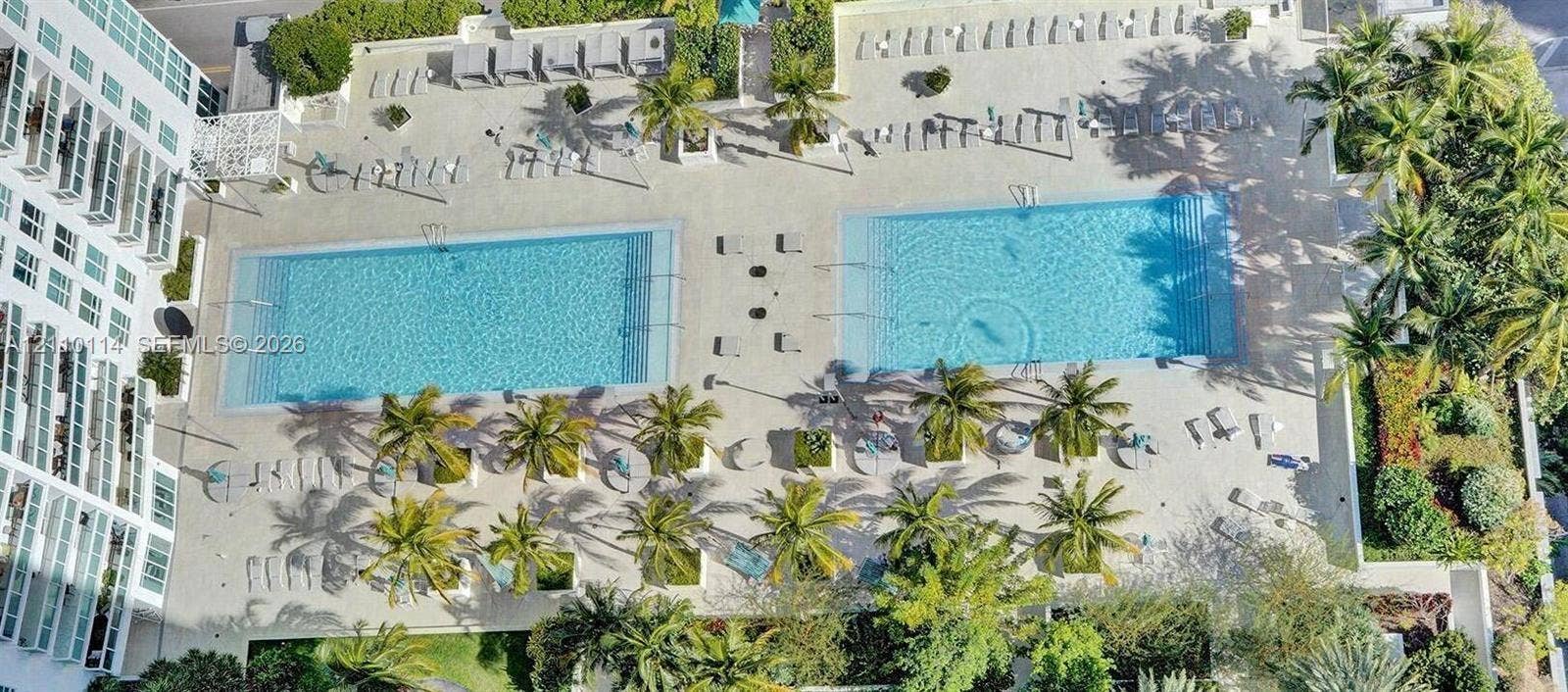 950 Brickell Bay Drive, #5108, Miami, Miami, FL 33131 Dual swimming pools featuring expansive stone-paved decking, integrated landscaping, and numerous palm trees