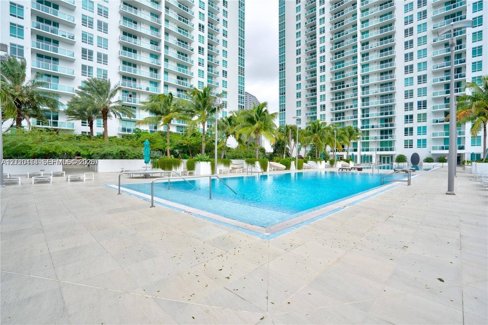 950 Brickell Bay Drive, #5108, Miami, Miami, FL 33131 Swimming pool with metal handrails, expansive stone-tile deck, and landscaped surroundings featuring mature palm trees