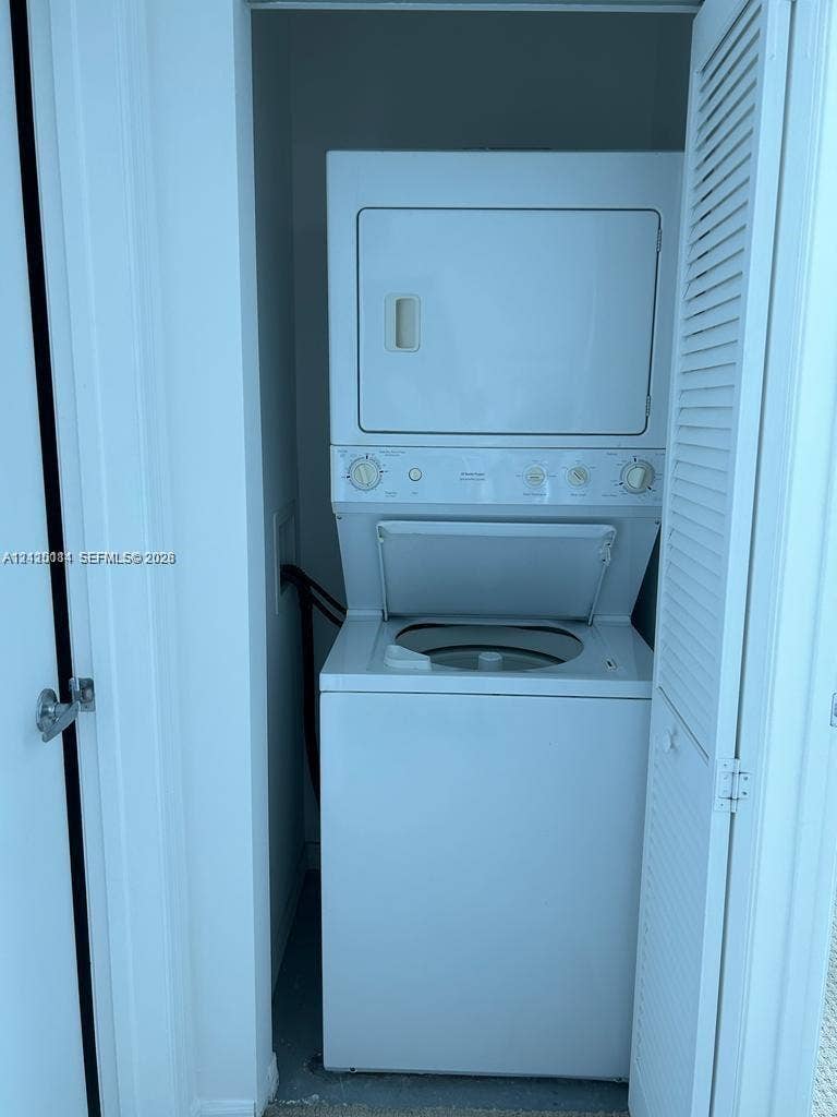 950 Brickell Bay Drive, #5108, Miami, Miami, FL 33131 Stacked washer and dryer unit housed within a closet featuring white louvered doors