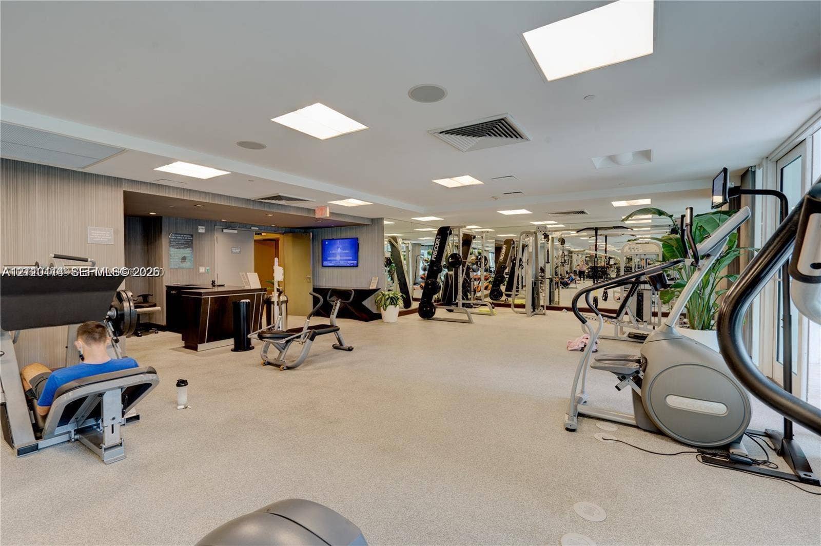 950 Brickell Bay Drive, #5108, Miami, Miami, FL 33131 Fitness center featuring neutral carpeting, recessed lighting, expansive wall mirrors, and built-in reception cabinetry