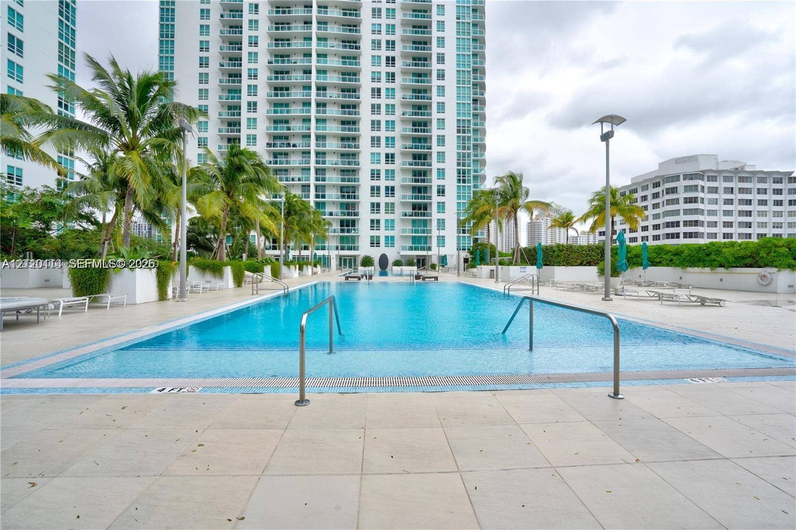 950 Brickell Bay Drive, #5108, Miami, Miami, FL 33131 Swimming pool with tile surround, stainless steel entry rails, and integrated landscaping featuring mature palm trees