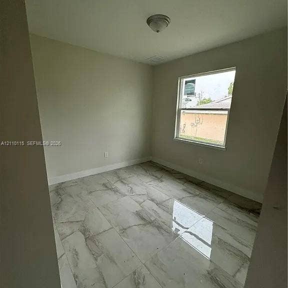 3304 11 Street W, #0, Lehigh Acres, FL 33971 Neutral-toned walls paired with large-format, glossy stone-finish floor tiling and a single-pane window