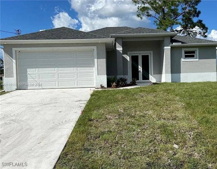 3304 11 Street W, #0, Lehigh Acres, FL 33971 Single-story exterior featuring a stucco facade, double-door entry, concrete driveway, and a two-car garage